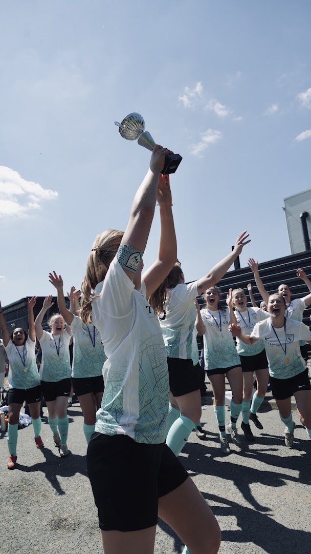 A South West Saints player lifts the cup as teammates celebrate behind her